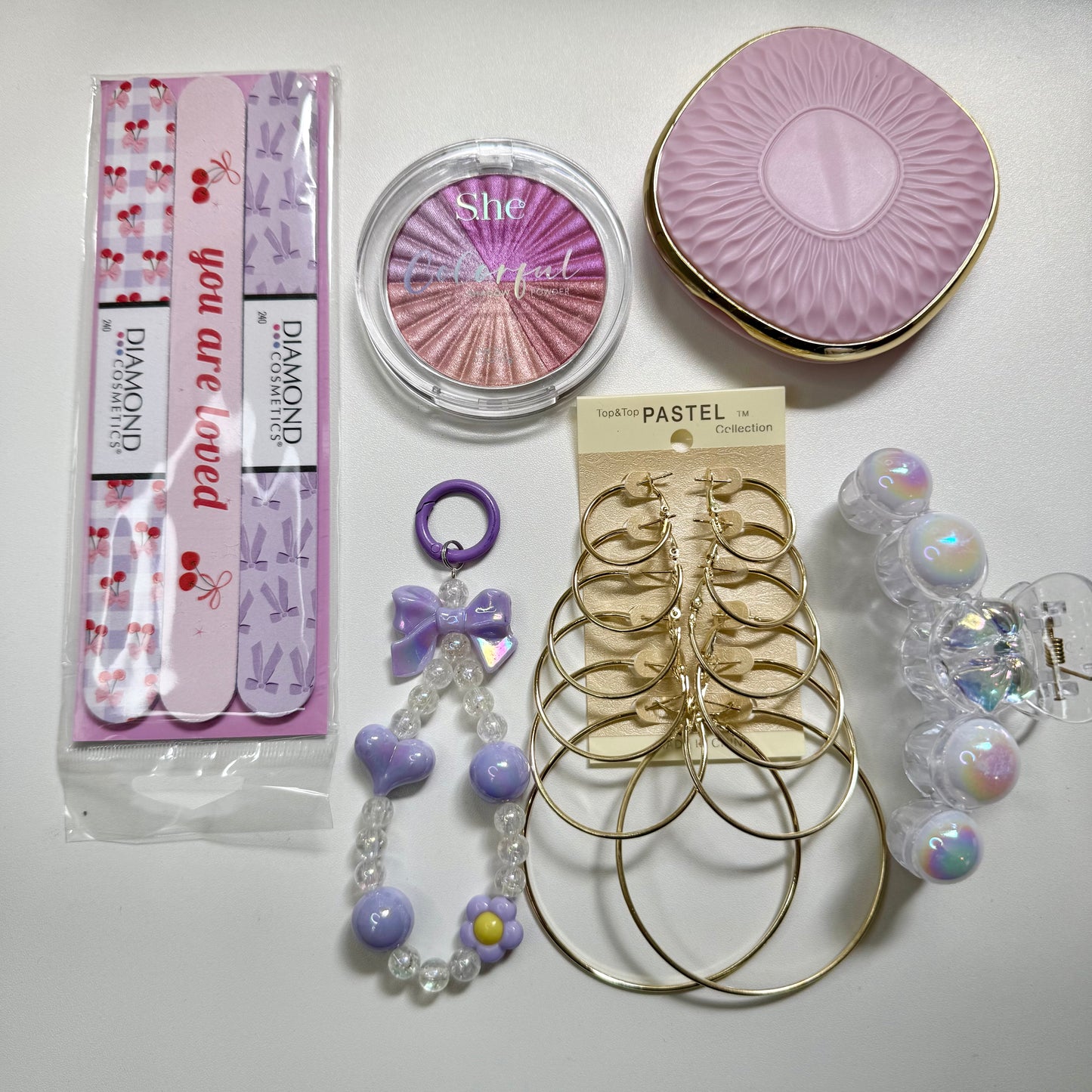 Collection of jewelry and beauty products including earrings, a compact mirror, and a bracelet