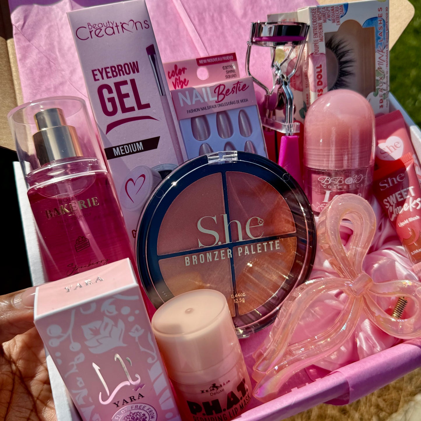 Unboxing pink beauty kit with tissue paper revealing lip care, makeup, and lashes inside gift box