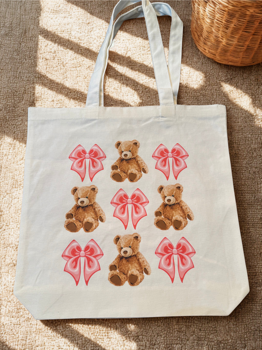 Tote bag with teddy bear and bow design on a textured surface