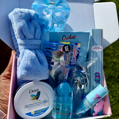 Gift basket with blue-themed items including a towel, cream, and bottles.