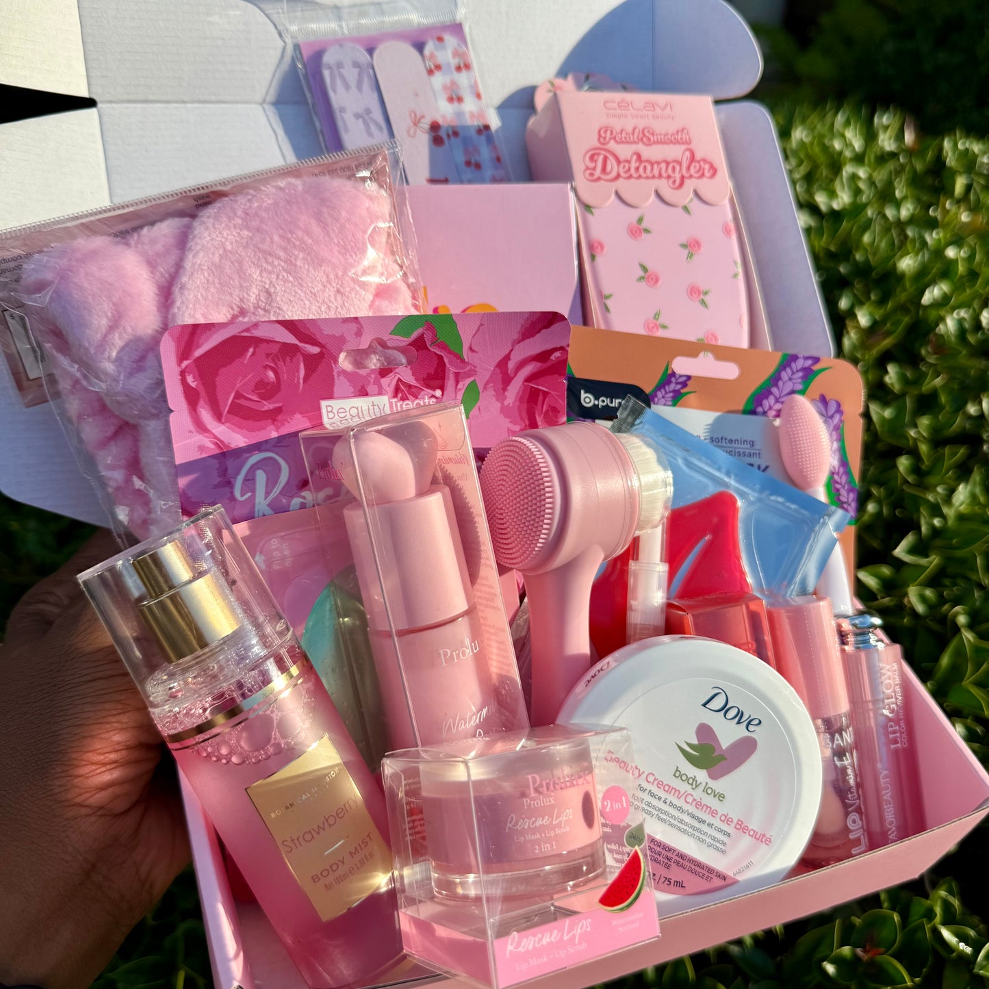 Assorted beauty products including a hairbrush, lip balm, and other items in a box outdoors.